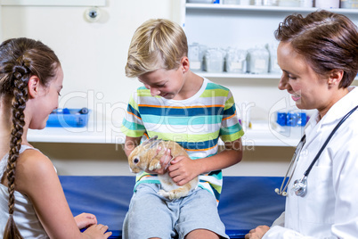 Little boy holding a rabbit surrounded by woman vet and little g
