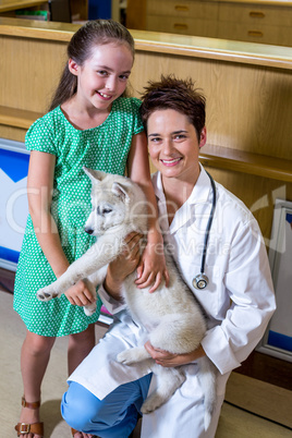 Portrait of little girl and woman vet holding a cute puppy