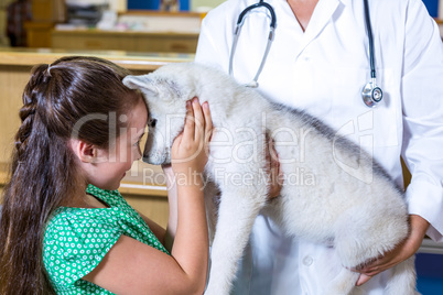 Portrait of little girl giving a hug to a puppy in vets arms