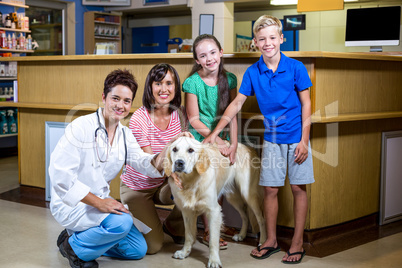 Woman vet and happy family smiling and posing with a dog