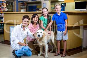 Woman vet and happy family smiling and posing with a dog