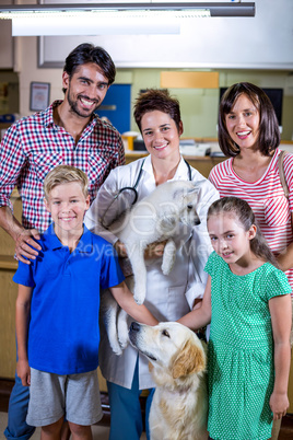 Woman vet holding a cute puppy and posing with a happy family