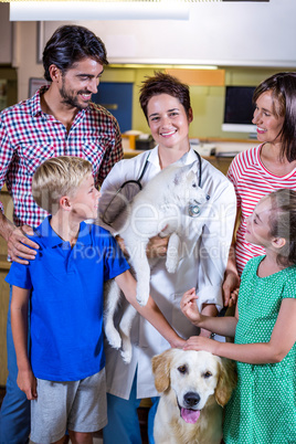 Woman vet smiling and holding a cute puppy surrounded by a happy