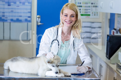 Woman vet smiling and writing puppys examination results on a cl