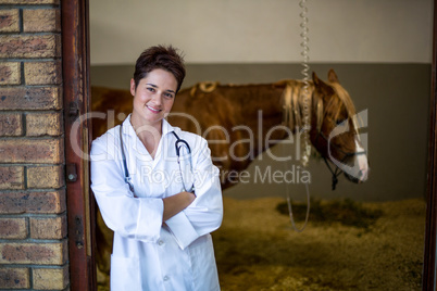 Portrait of smiling woman vet posing in front of a sick horse