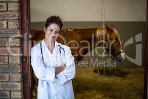 Portrait of smiling woman vet posing in front of a sick horse
