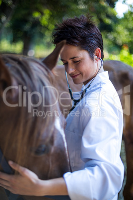 Portrait of woman vet examining a horse