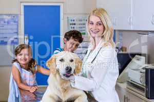 Portrait of woman vet holding a dog in front of two children