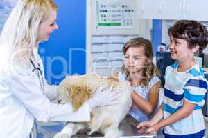 Woman vet examining a dog with two children