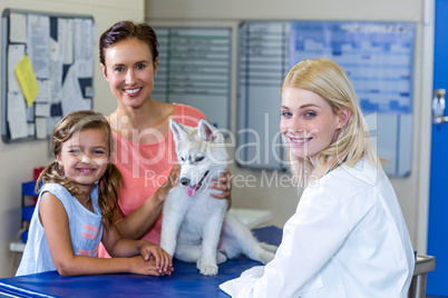 Woman vet and puppys owners smiling and posing