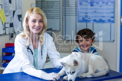 Woman vet and little boy smiling and posing with a cute puppy