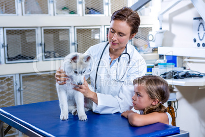 A woman vet examining a dog in front of a little girl