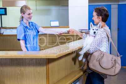 A woman vet giving a paper to her customer