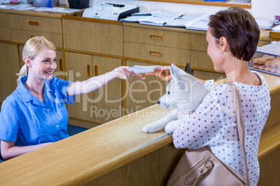 A woman vet giving a paper to her customer