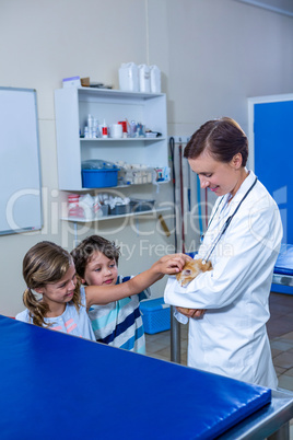 A woman vet and children petting a rabbit