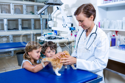 A woman vet and children petting a kitten