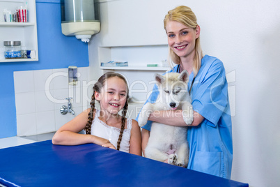 A woman vet posing and smiling with a dog and little girl