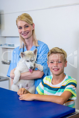 A woman vet posing and smiling with a dog and little boy