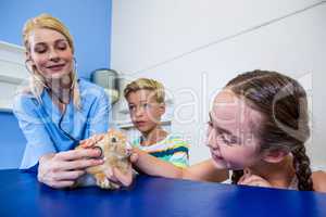 A woman vet examining rabbit with children