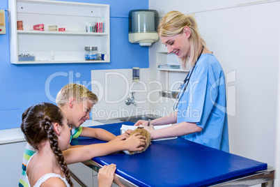 A woman vet taking notes while children petting a rabbit