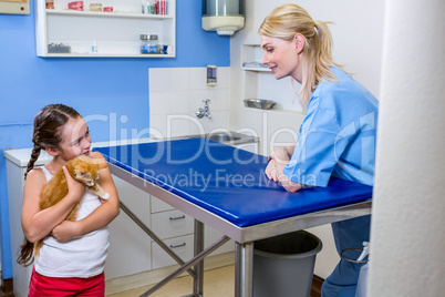 A woman vet looking a little girl bringing a cat