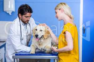 A man vet and his customer petting a dog