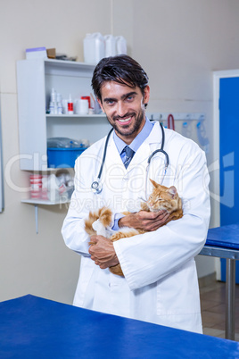 Smiling vet holding a cat in his arms