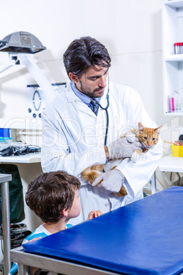 A vet holding a cute cat with a boy watching him