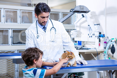 A vet and a child trying to giving water to a cat