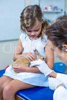 A rabbit hold by a little girl is receiving care