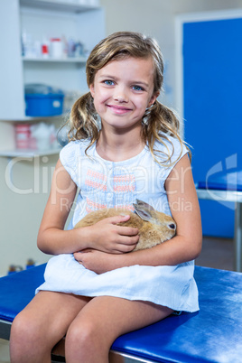 Cute girl holding her rabbit and looking at the camera