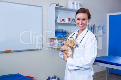 A smiling vet holding a cute kitten looking at the camera