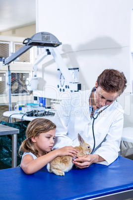 A vet and a children are taking care of a rabbit