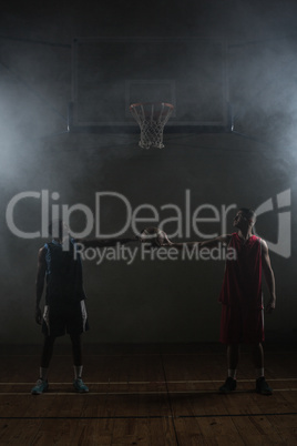 Two basketball player holding a single basketball