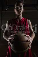 Portrait of basketball player unsmiling and holding a basketball