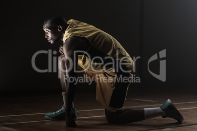 Basketball player preparing to play with knee on the floor and l