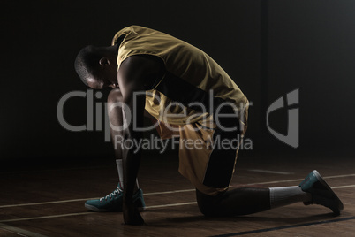 Basketball player preparing to play with knee on the floor and h