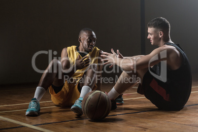 Basketball players sitting on floor talking together