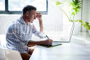 Serious man working at desk with laptop