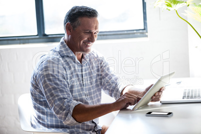 Smiling man working at desk with tablet