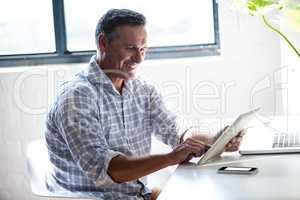 Smiling man working at desk with tablet