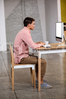 Profile view of young business man working at computer desk