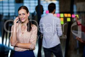 An attractive businesswoman having a phone call while colleagues