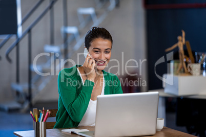 Smiling woman working at desk and having a phone call