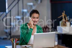Smiling woman working at desk and having a phone call
