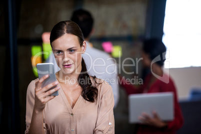 An attractive businesswoman texting and standing