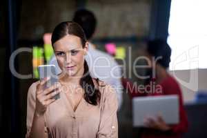 An attractive businesswoman texting and standing
