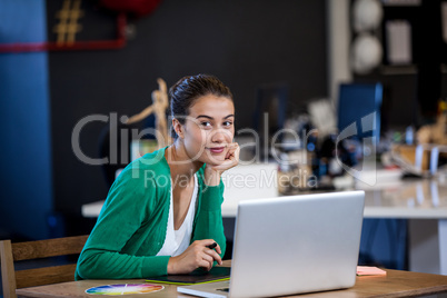 Businesswoman smiling at camera while seating at desk