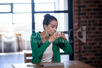 Portrait of young businesswoman drinking a coffee while working