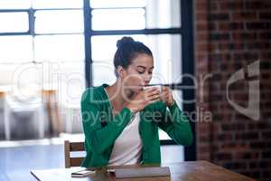 Portrait of young businesswoman drinking a coffee while working